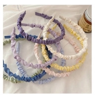 Detailed view of pleated fabric headbands in assorted pastel colors on white background