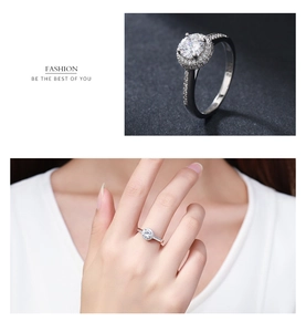 Detail of s925 sterling silver halo ring with pavé diamond band on hand and textured surface