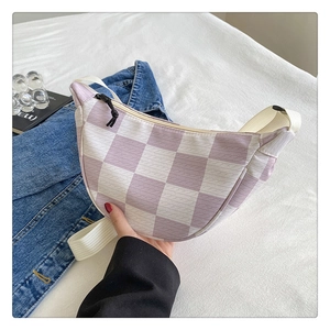 Detail of a lavender checkered crescent bag with white strap on a lifestyle backdrop
