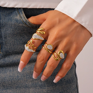Detailed shot of gold geometric leaf and wave rings with rhinestones on denim