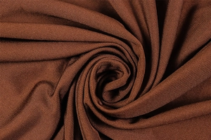 Macro shot of dark brown ribbed knit fabric texture with elegant draped spiral patterns