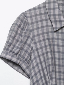 Detail of grey-blue plaid dress showing lapel collar and pleated puff sleeve texture