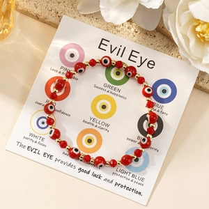 Λήψη macro του κόκκινου βραχιολιού Evil Eye με χρυσές λεπτομέρειες σε κάρτα δώρου
