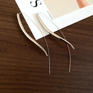 Macro view of long silver teardrop earrings with high-polish finish on minimalist hooks
