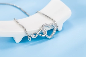 Macro detail of silver heart and infinity symbol bracelet with zircon stones