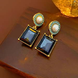 Detail of vintage gold earrings with white pearl and blue faceted gemstone pendants