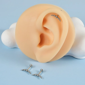 Curved stainless steel barbell ear studs with seven silver beads on a blue backdrop