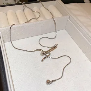 Minimalist silver snake chain necklace with abstract curved pendant in a jewelry box