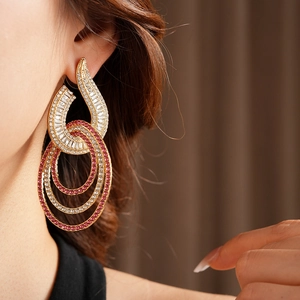 Close-up of golden hollow circle earrings with pink and clear cubic zirconia on ear