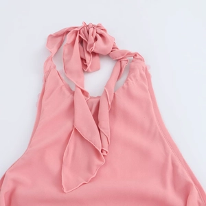 Detail van roze chiffon halterjurk met een fijne strik bij de nek en open schouders