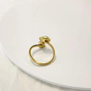 Detail of adjustable gold ring with a single white pearl on a minimalist white tray