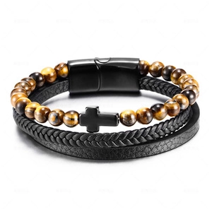 Macro detail of multilayer black braided leather bracelet with tiger eye beads and cross charm