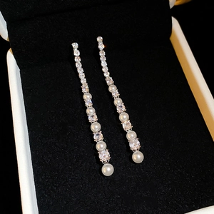 Boucles d'oreilles pendantes en argent avec zircons et perles sur velours noir
