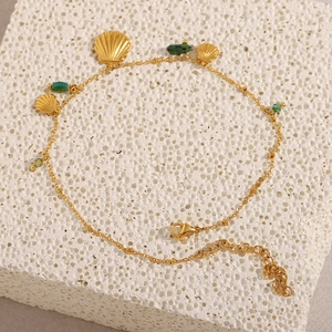 Détail de breloques en coquillage doré 18 carats et perles vertes sur une chaîne fine