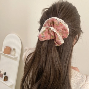 Close-up of pink floral hair scrunchie with white lace trim worn on hair