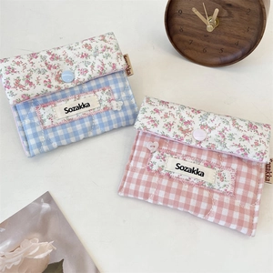 Close-up of quilted floral sanitary pouch in blue and pink cotton with button fastener