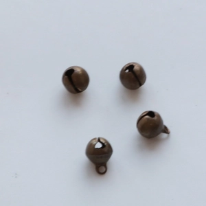 Detail of four bronze metal bells with hanging rings on a clean white background