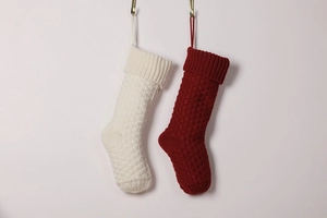 Detail of knitted Christmas stockings in cream and wine red with hanging loops
