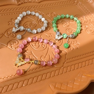 Détail de bracelets en perles d'oeil de chat avec pendentifs papillon sur plateau