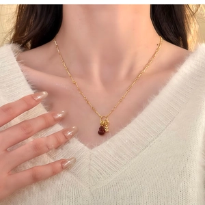 Close-up of gold-plated necklace with small red gourd pendant on a female model