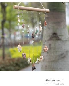 Detail of bohemian crystal wind chime with natural raw stones and wooden bar hanger