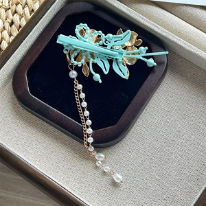 Détail de la pince tulipe bleu sarcelle avec émail doré et longs pompons en perles