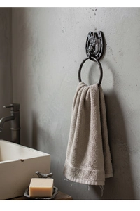 Detail of vintage cast iron horseshoe towel ring with embossed horse head on stone wall