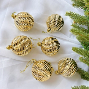 Nahaufnahme von goldenen Weihnachtskugeln mit Spiralmuster auf Stoff und Tannenzweigen