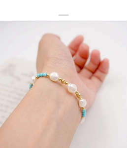 Detailed view of turquoise and freshwater pearl beaded bracelet worn on a woman's wrist