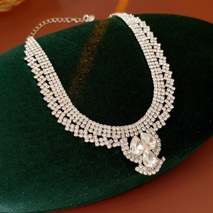 Close-up of layered diamond drop pendant necklace on green velvet display