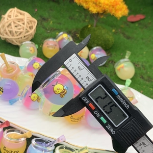 Caliper measuring the 21.5mm diameter of a colorful miniature resin honey jar pendant