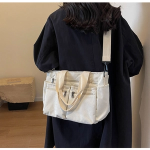 Detail of off-white corduroy crossbody bag showing multi-pocket design and strap texture