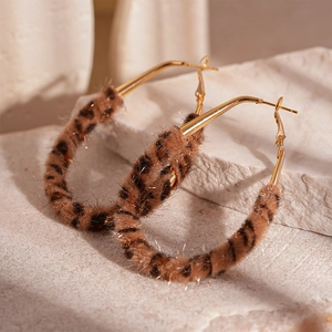 Macro view of gold hoop earrings with brown leopard print faux fur texture details