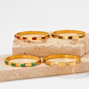 Macro view of gold stainless steel bangles set with colorful zircon stones on stone base