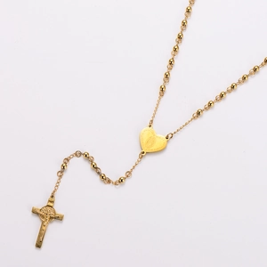 Macro shot of gold stainless steel rosary necklace with heart and cross charms