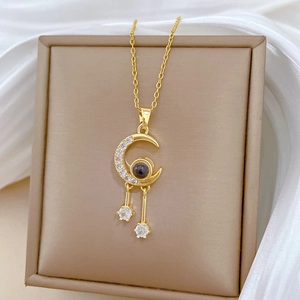 Macro detail of gold moon pendant necklace with inset gemstone on beige jewelry box