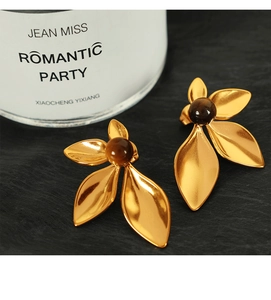 Detailed view of 18K gold flower earrings featuring a brown bead and petal texture