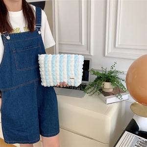 Blue and white striped cloud bubble pouch held by model in a clean lifestyle home setting