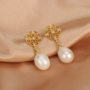Macro detail of 18K gold-plated earrings with freshwater pearls and purple zircon stones