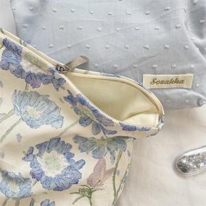 Detailed close-up of floral print and blue textured fabric makeup bags with metal zippers