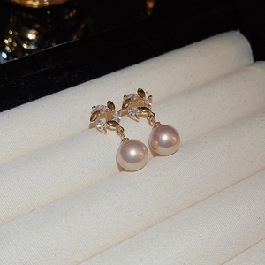Macro view of gold-plated leaf earrings with sparkling zircons and elegant white pearls