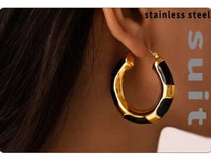 Detail of large gold and black leopard pattern hoop earrings worn on a female model