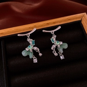 Detailed view of silver flower earrings with green crystal and sparkling rhinestones