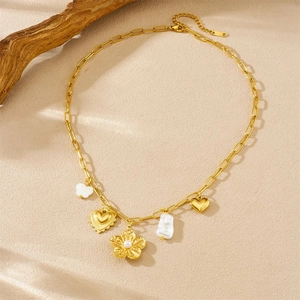 Collier en acier doré avec fleurs en perles et breloques cœur sur fond beige chaleureux