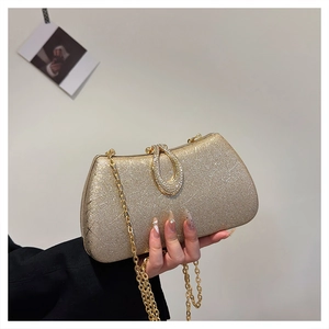 Detailed close-up of a golden sequin evening clutch with rhinestone teardrop clasp and chain