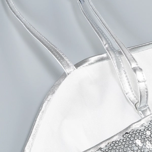 Detailed macro view of silver sequins and white fabric with delicate spaghetti strap