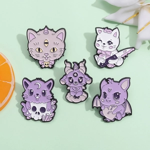 Close-up of five pastel goth enamel pins featuring purple cats, skulls, and crystal designs