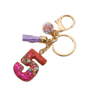Glittery number 5 keychain with purple tassel and star sequins in a clear glass ball