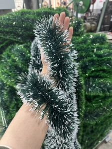 Dark green Christmas tinsel garland with white tips held in a warehouse setting