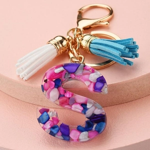 Close-up of letter S resin keychain with colorful gravel, tassel and gold-tone ring